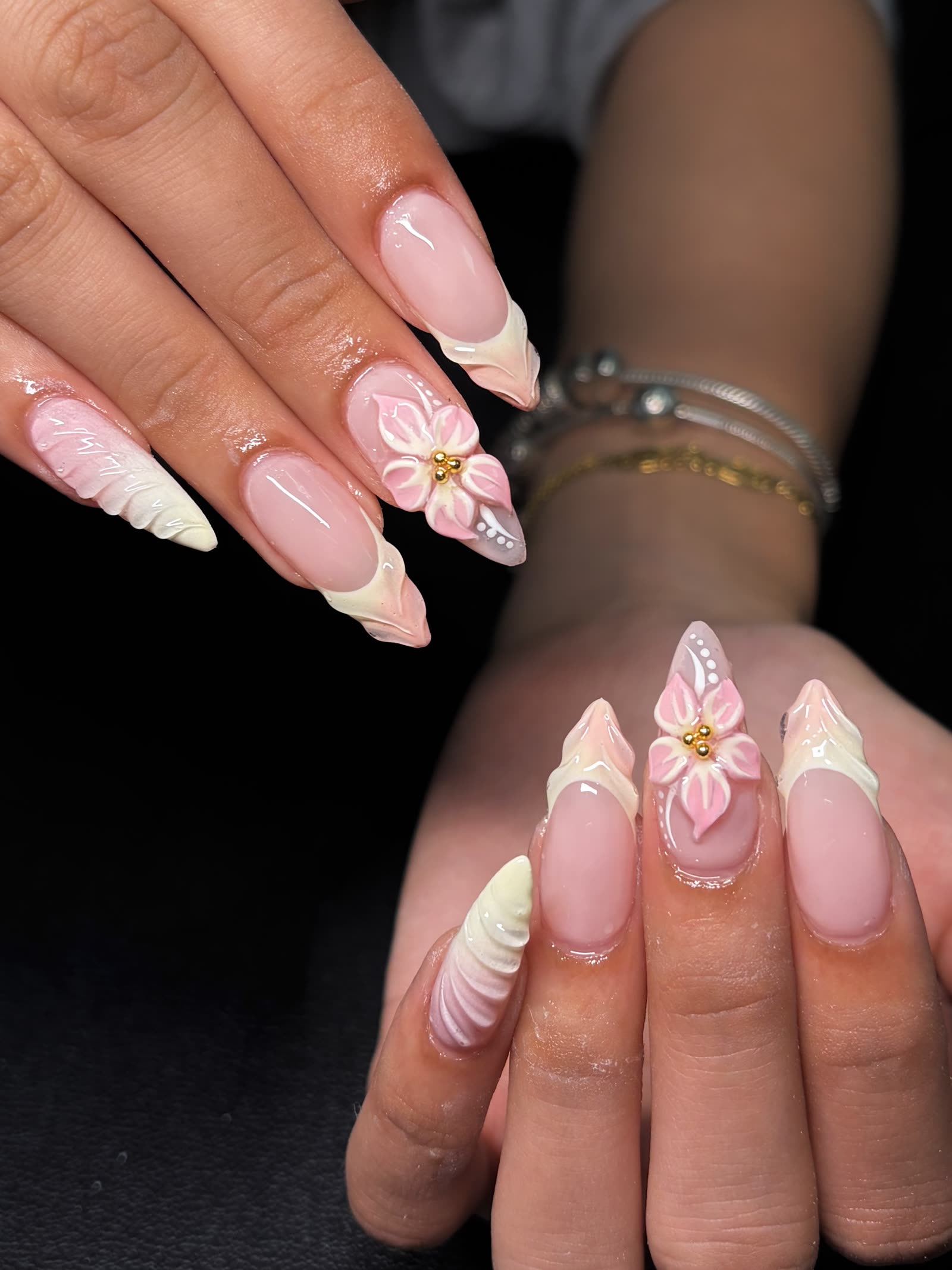 Soft pink and cream almond nails with 3D sculpted flowers, gold beads and ruffled tips