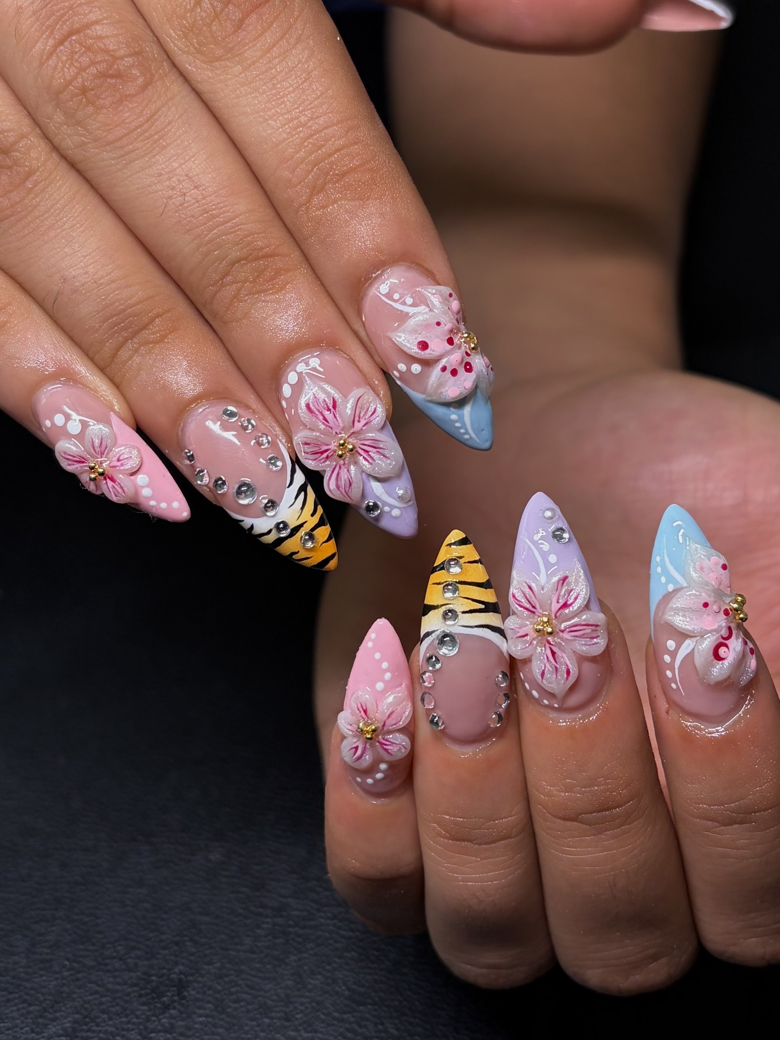 Stiletto nails in pink, blue and lilac with a tiger-stripe accent, 3D sculpted flowers, gold beads and clustered rhinestones